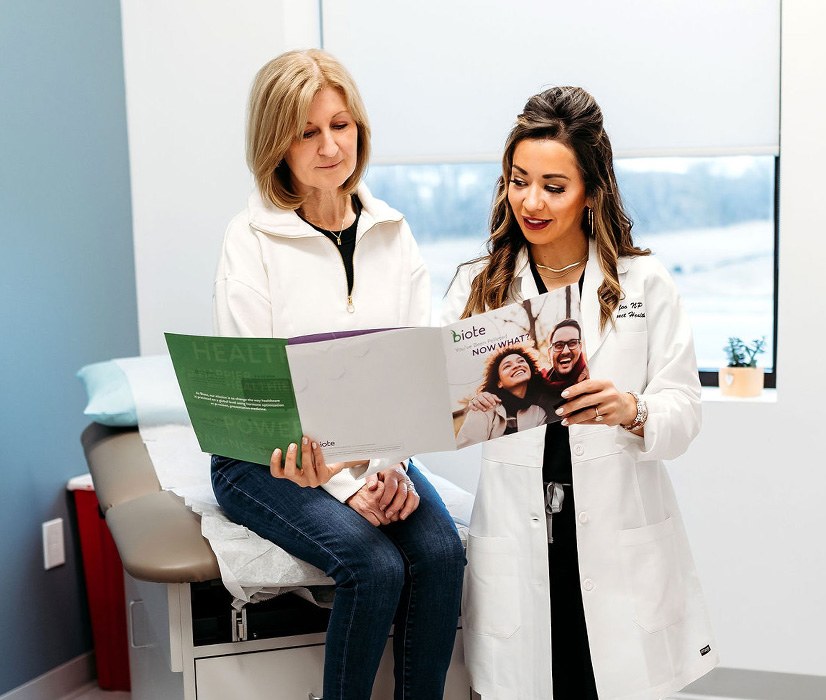 Lexi Yoo, NP discussing biote brochure with female patient during hormonal imbalances and thyroid health visit.