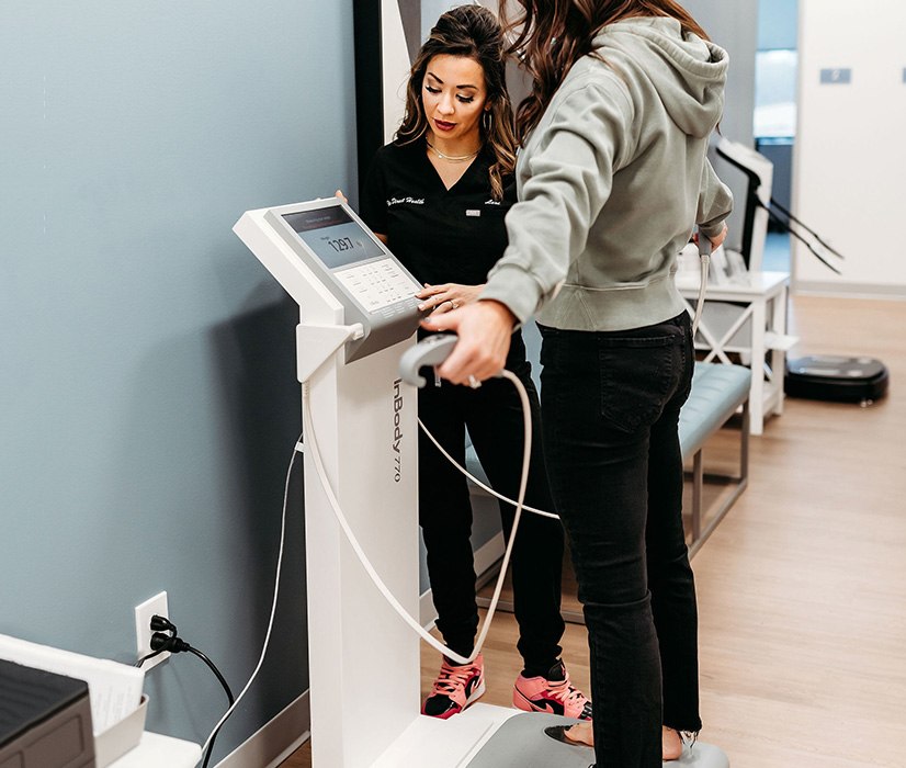 Lexi Yoo, NP with female patient using InBody machine during weight optimization visit.