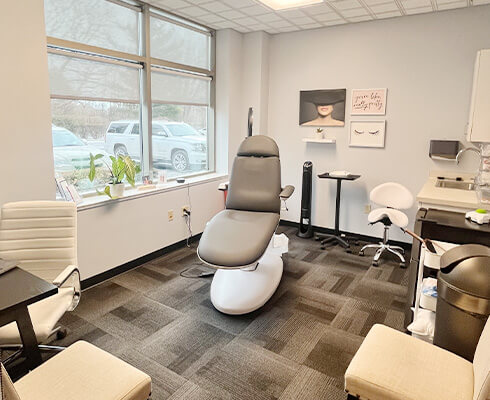 Consultation room at Yoo Direct Health Greenwood has seating, medical equipment, art.